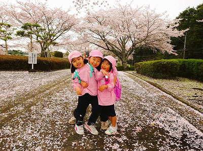 桜の前でポーズする子どもたち