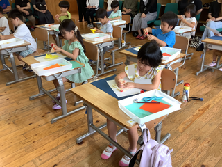 折り紙を台紙に貼るこどもたち